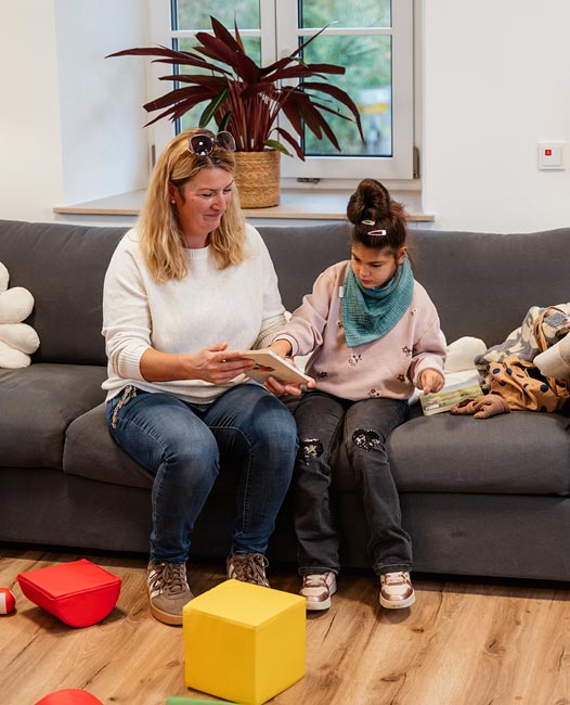 Betreuerin und Pflegekind auf der Coach beim Spielen